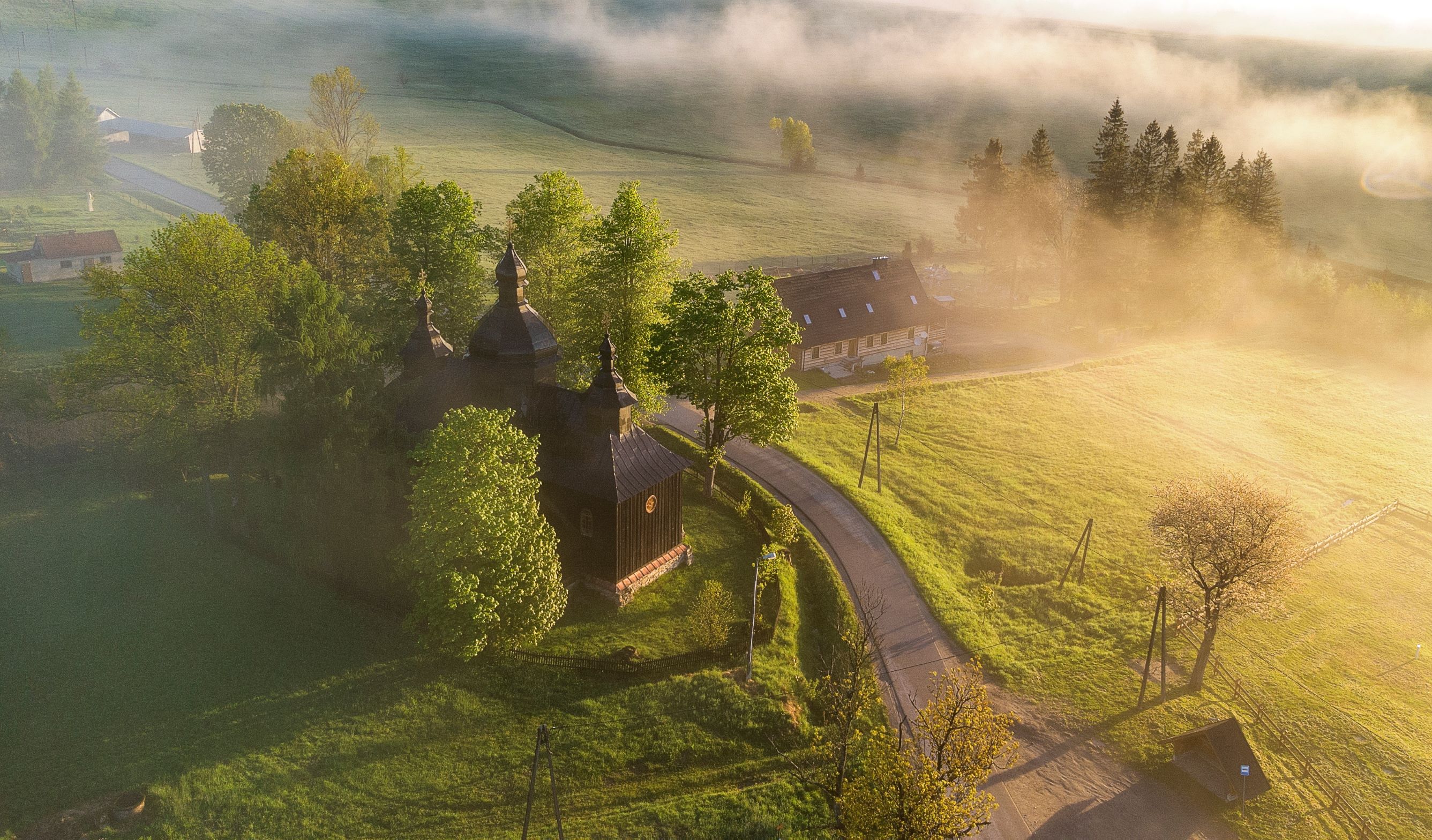 Widok na drogę i drewnianą kaplicę z lotu ptaka.