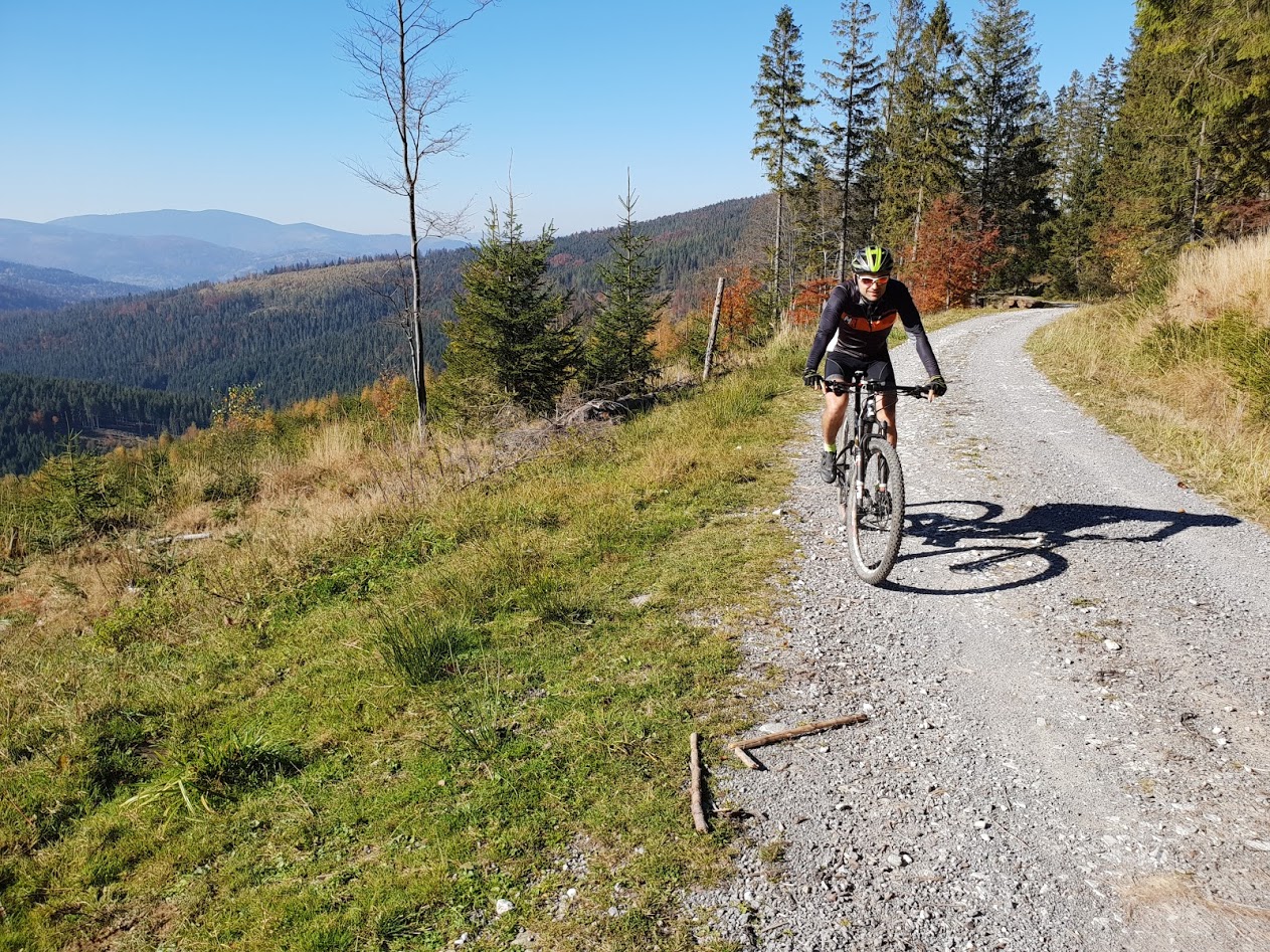 Rowerzysta jedzie po ścieżce szutrowej w tle widać góry